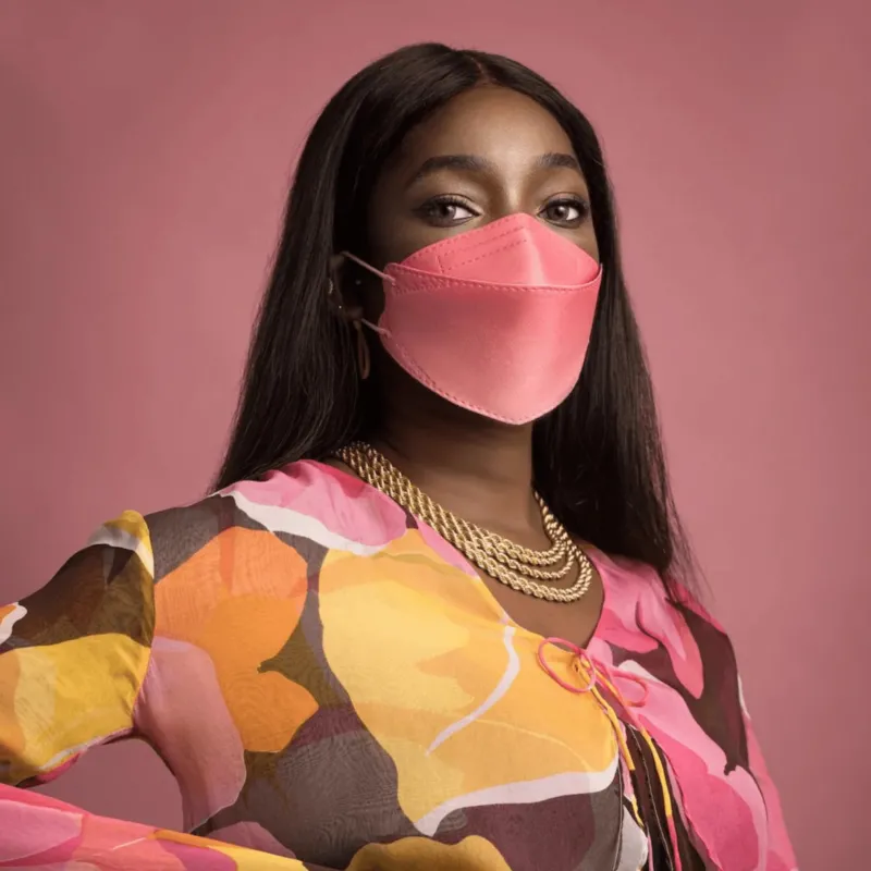 Person trägt rosa Altruan Designer-FFP2-Maske vor rosa Hintergrund.